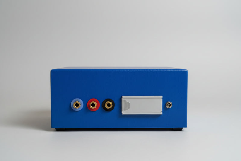 The rear view of a AMCO audiometer, featuring three audio jacks (blue, red, black) with gold-plated connectors and a blank white label area.