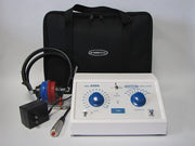 Ambco 650A TENS unit muscle stimulator with a white control panel, blue dials, attached black and red electrode leads, a black power adapter, and a black zippered carrying case on a light gray background.