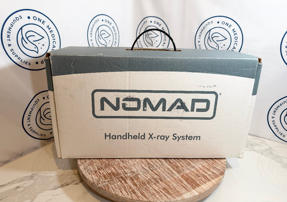 Nomad handheld X-ray system packaging on a wooden surface with branded background.