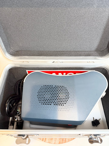 A light blue BioLite Ceralas laser device with a perforated front grille, shown inside an open silver hard carrying case with gray foam lining. 