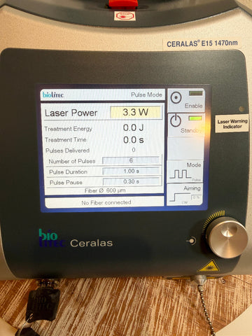 A close-up of a Ceralas BioLite Ceralas laser device with its digital control screen active, showing settings like laser power and treatment time, placed on a wooden surface.