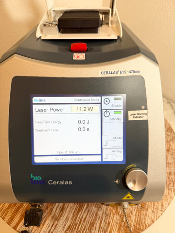 A BioLite Ceralas laser device with a digital display screen showing laser power and treatment settings, resting on a wooden surface.
