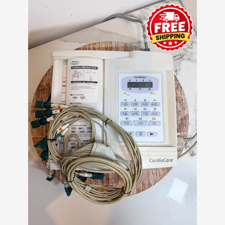 CardioCare cardiac monitor with attached lead wires and a printed instruction booklet, placed on a round wooden tray with a red 'FREE SHIPPING' badge overlay in the top right corner.