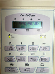 Close-up of a CardioCare electronic device keypad with an LCD display showing the text 'NAME AGE SEX'. The keypad has light purple buttons with black text on a white faceplate.
