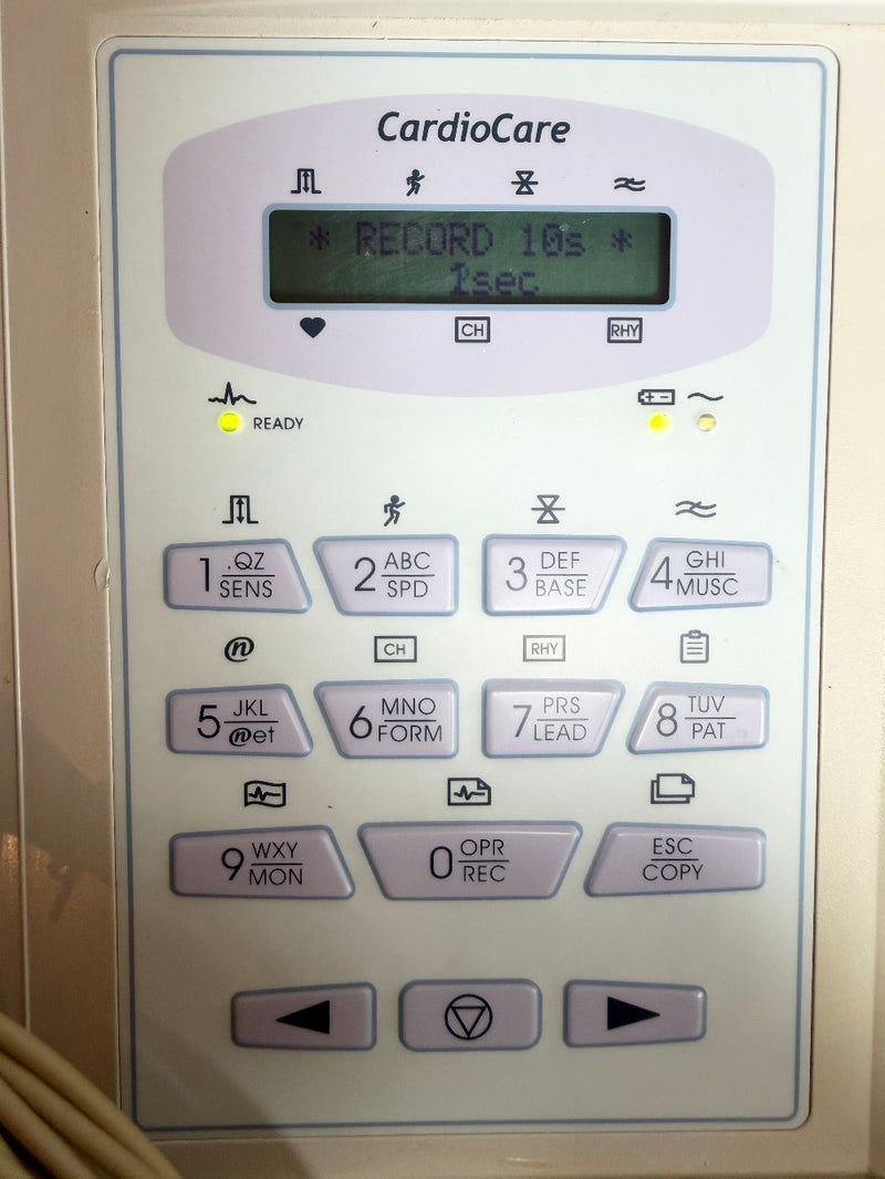A close-up of a CardioCare electronic device control panel with a small display screen and multiple labeled buttons, photographed against a light neutral background.