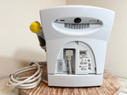 The back of a white Chattanooga Intelect Legend XT 2760 device, showing the power cord, USB cable, ventilation slots, and branding on the back panel.