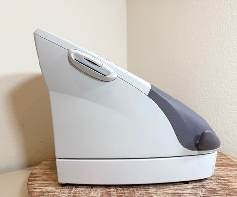A white and gray Chattanooga Intelect Legend XT 2760  device, shown from a side angle on a wooden surface against a beige wall.