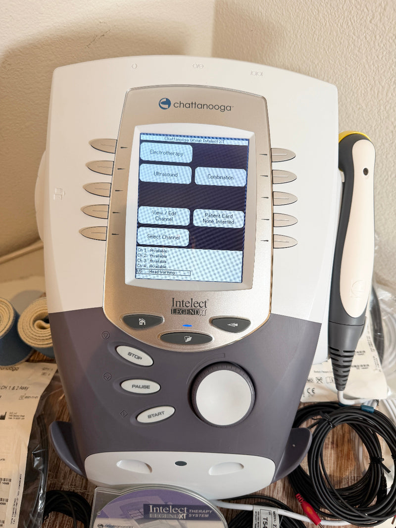 A CChattanooga Intelect Legend XT 2760 device with its handheld wand, shown on a desk with paperwork in the background.