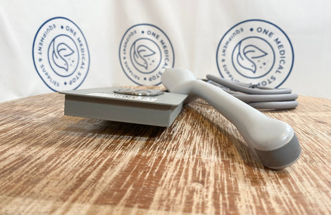 Gray handheld device on a wooden surface with 'One Medical' branding in the background.