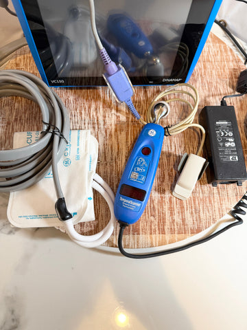 Blue GE Carescape Dinamap VC150 Vital Signs Monitor on a wooden surface with cables.