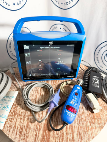 Blue GE Carescape Dinamap VC150 Vital Signs Monitor device with screen on a wooden surface, surrounded by cables and tools.