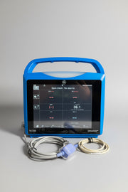 Blue GE Carescape Dinamap VC150 Vital Signs Monitor device with screen displaying readings on a wooden surface.