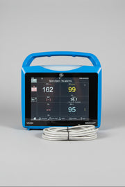 Blue GE Carescape Dinamap VC150 Vital Signs Monitor device with digital display on a wooden surface, branded 'GE' and 'Dinamap'.