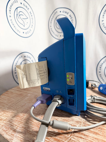 Blue GE Carescape Dinamap VC150 Vital Signs Monitor device with a receipt on a wooden surface.