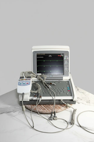 An EKG/ECG monitor machine with a built-in keyboard and screen, connected to multiple lead wires and a separate handheld pulse/ECG controller.