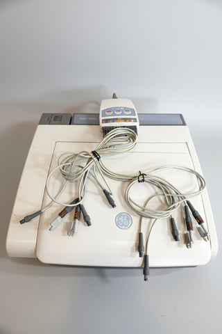 A GE EKG monitor machine in white, with multiple attached gray and black wires and leads laid out on top.