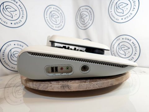 A white GSI AudioStar Ultrasound machine, resting on a round wooden coaster in front of a white backdrop.