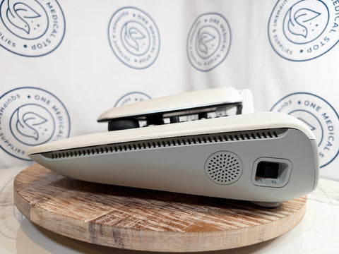 A white GSI AudioStar Ultrasound machine, resting on a round wooden board in front of a branded white backdrop with circular logos.