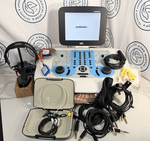 A GSI AudioStar Ultrasound machine  audio mixing console with a built-in monitor screen, shown with its accessories including a microphone, multiple cables, a carrying case, and earplugs on a white marble surface against a branded backdrop.