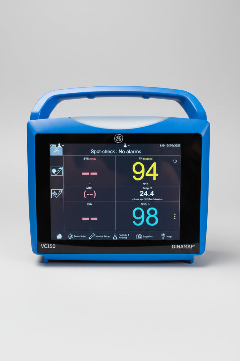 A blue GE Dinaram VC150 pulse oximeter sitting on a wooden table against a beige wall, showing a spot-check screen with readings of 94 and 98.