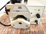 A close-up of a cream-colored KMI flow meter pump.