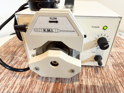 A close-up of a cream-colored KMI flow meter pump.