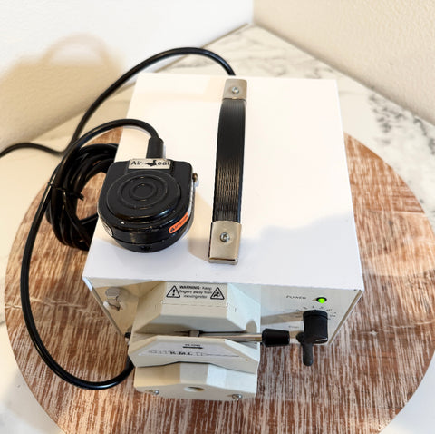 A white KMI flow meter pump with a black power cord and a black-and-silver handle.