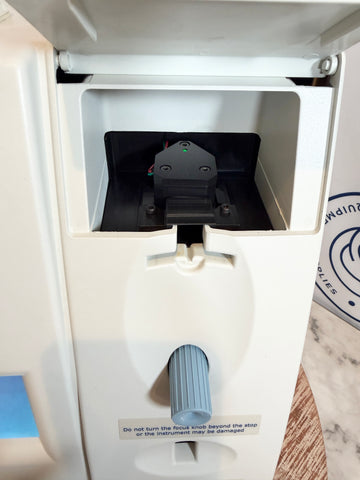 Close-up of a white dispenser with a black component inside, on a marble surface.