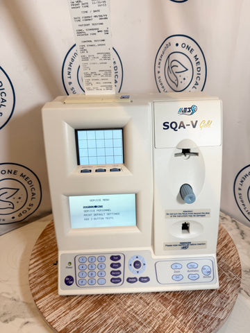 Medical device labeled 'SQA-V' on a wooden surface with a white background featuring 'One Medical' logos.