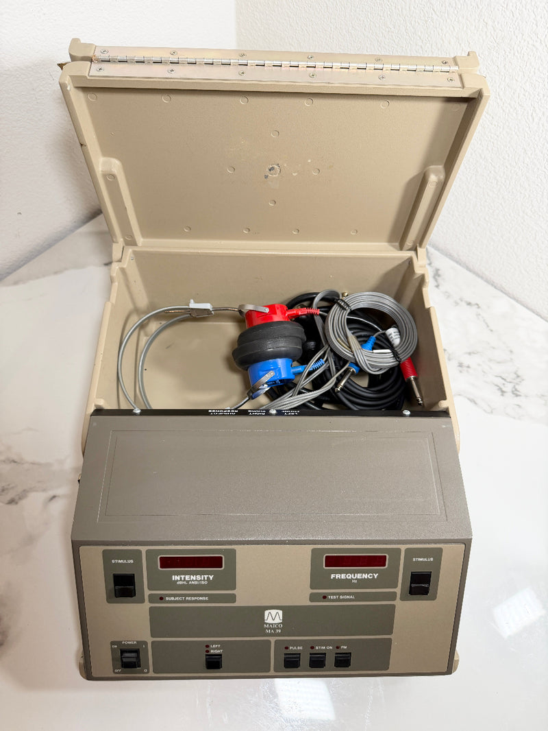 An open beige and gray Maico MA39 Portable Diagnostic Audiometer device with attached tubing and a red-and-blue regulator, photographed on a white marble-like surface against a white wall.
