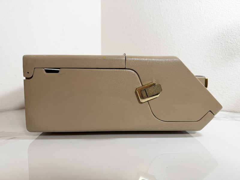 A Maico MA39 Portable Diagnostic Audiometer cover with a gold-toned latch, shown from a side profile on a white surface against a white wall.