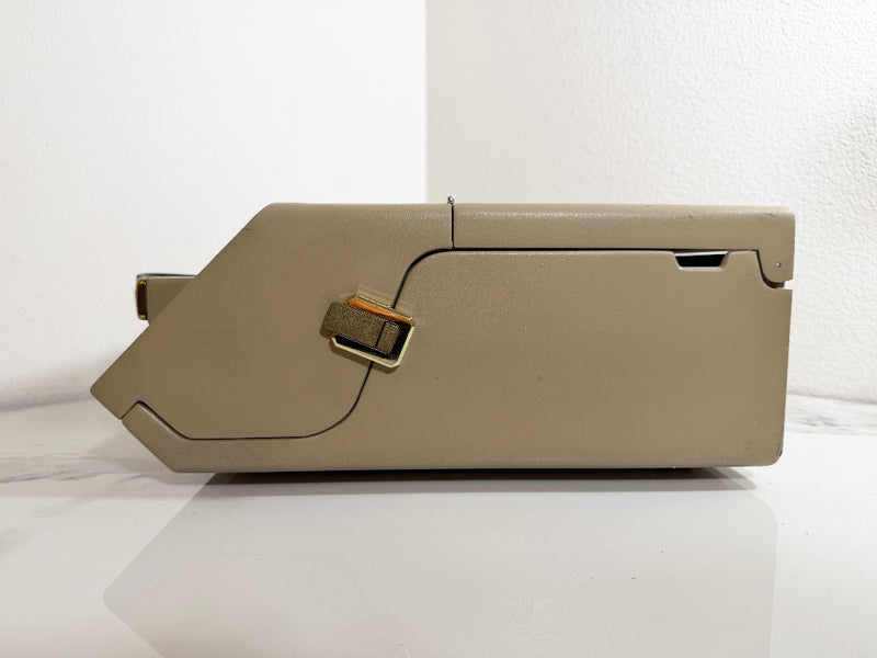 A Maico MA39 Portable Diagnostic Audiometer with gold-toned metal accents, photographed from the side against a white wall and white surface.