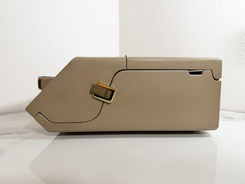 A Maico MA39 Portable Diagnostic Audiometer with gold-toned metal accents, photographed from the side against a white wall and white surface.