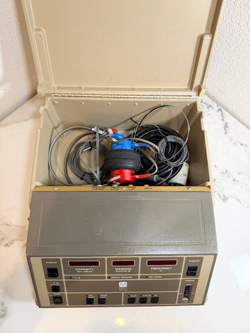 An open beige Maico MA40 Portable Diagnostic Audiometer box with a front panel of switches, dials, and labels, revealing tangled black cables and a blue-and-red component inside.