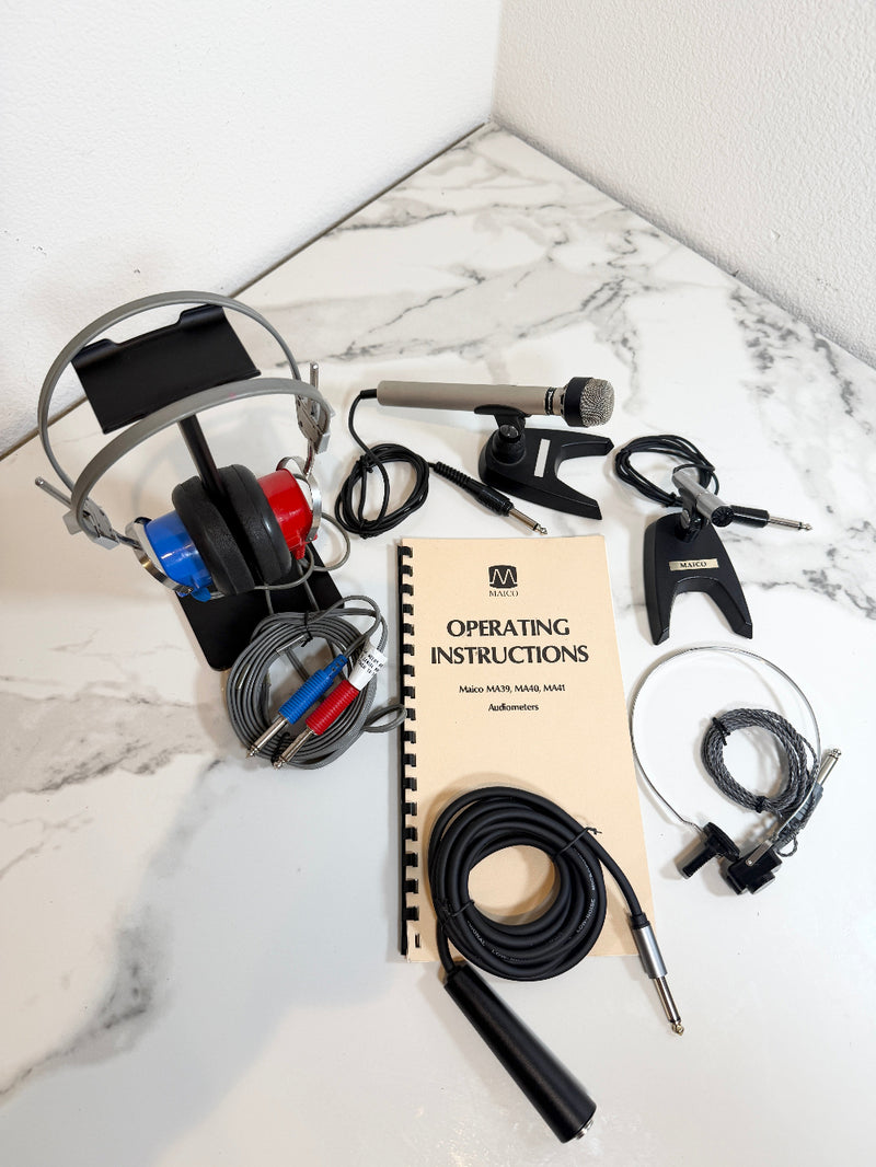 A complete audio interface and headphones kit laid out on a white marble surface, including over-ear headphones, a microphone, cables, an operating instructions booklet, and an audio adapter.