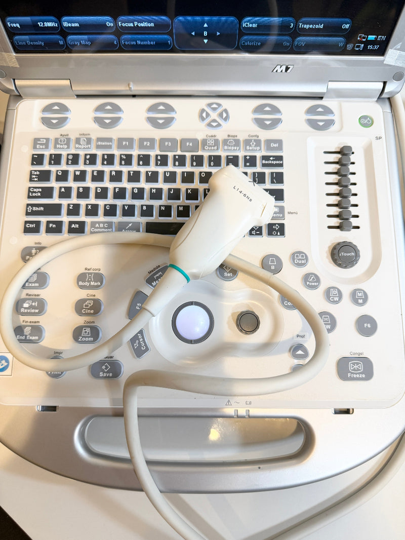 An ultrasound machine with a white control panel, black keyboard, and attached white ultrasound probe with cable, photographed from above.