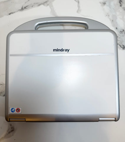 A silver Mindray portable medical device with a handle on top, photographed from above on a white marble-patterned surface.