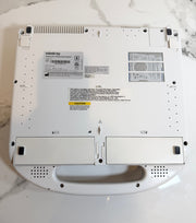 The underside of a white Mindray handheld ultrasound device, showing the brand label, ventilation grilles, and handle cutout, photographed on a white marble surface.