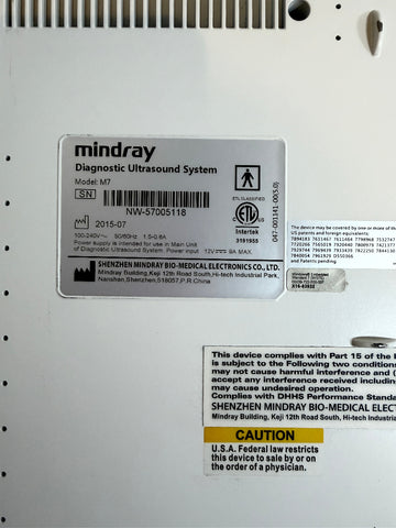 Close-up of the back panel of a Mindray diagnostic ultrasound system, showing the model M7 label, certification stickers, and regulatory text on a white metal surface.