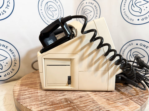 Beige electronic device with black cord on a wooden surface, branded background