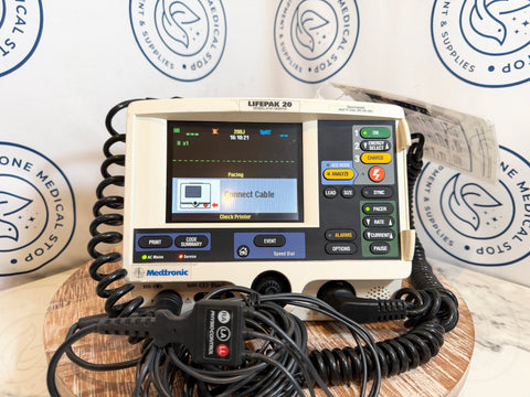 Heart monitor device with coiled cables on a wooden surface, branded with 'One Medical Stop'.