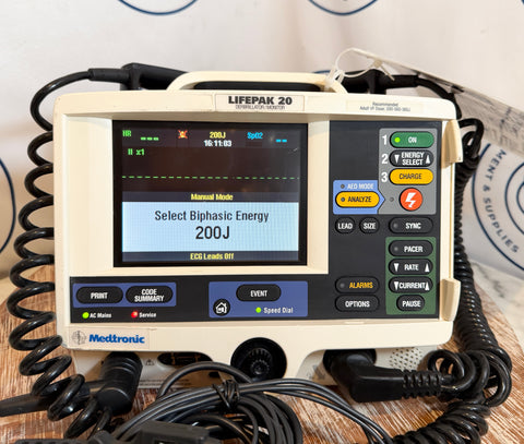 Medtronic Lifepak 20 defibrillator on a wooden surface with cables.
