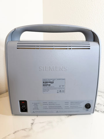 A Siemens Acuson Cypress Portable Ultrasound shown from the back, featuring a gray handle, vented top, power switch, and technical specifications label on a light marble surface.