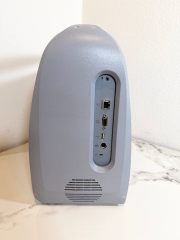 The rear view of a Siemens Acuson Cypress Portable Ultrasound with various audio and networking ports, standing on a white marble surface against a white wall.