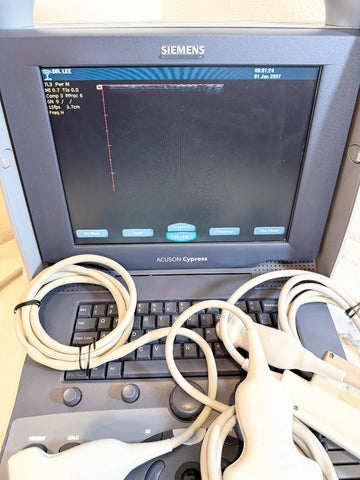 Siemens Acuson Cypress portable ultrasound machine with a gray console, black screen, keyboard, and multiple white probe cables in the foreground.