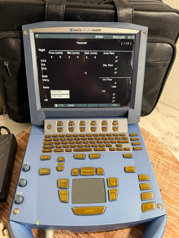 A blue and gray SonoSite MicroMaxx Portable Ultrasound System with a screen displaying vascular ultrasound settings, resting on a wooden surface with a black bag in the background.