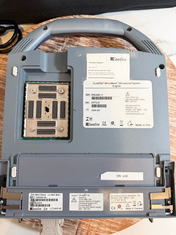 An open SSonoSite MicroMaxx Portable Ultrasound System, showing the connection components, labels, and metal contacts, photographed on a wooden surface.