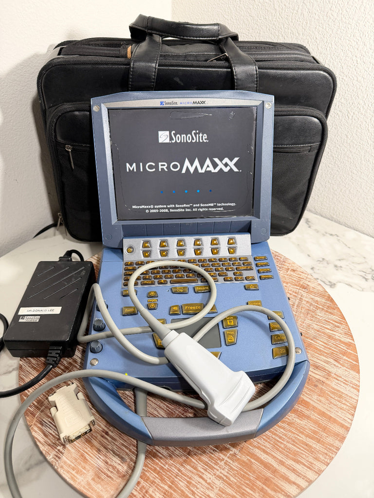 A SonoSite MicroMax portable ultrasound machine in blue and gray, shown open with its keyboard, cables, and probe in front of a black carrying case on a marble surface.