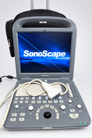 A SonoScape portable ultrasound machine with its screen on and attached probe, sitting on a wooden surface with a black carrying case behind it.