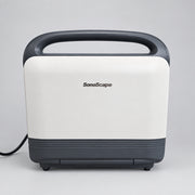 A SonoScape portable ultrasound machine with a cream-colored body, dark gray handle and base, sitting on a wooden surface against a white wall.